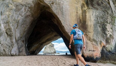 Traveller walking on the sand at Cathedral Cove in the Coromandel Peninsula, New Zealand