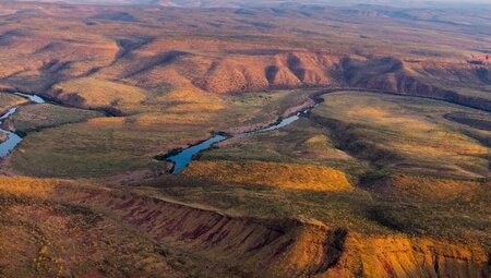 Aerial view of river running through the orange green of El Questro Wilderness Park, Western Australia