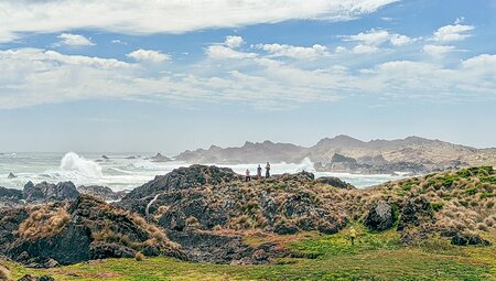 Travellers stand at the edge of a prominatory coastline on the Tarkine Coast in Tasmania