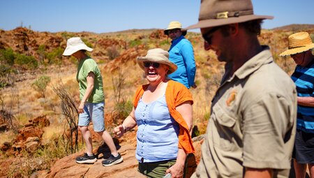 Intrepid travellers of different ages laugha and smile in the orange outback of Western Australia