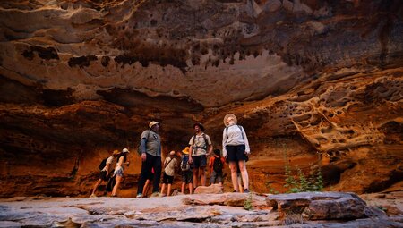 Travellers and leader marvel at the rock faces of a cave in Cathedral Gorge walk