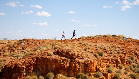Travellers walking a high orange ridgeline in the Kimberley Western Australia