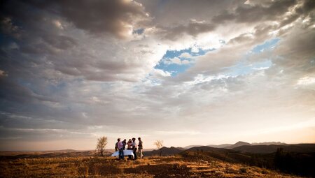 Wide view of travellers having a drink on a hilltop during sunset, Arkaba, South Australia