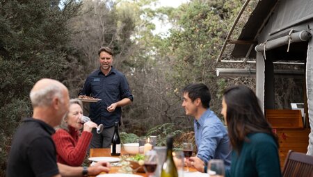 Lunch being served during outdoor group lunch, while travellers sip on wine, Maria Island, Australia