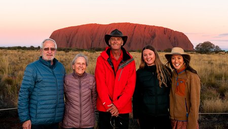 Leader and Travellers posing in front of Uluru at sunset