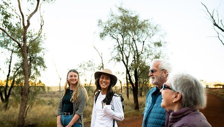 Group of travellers laugh against the Red Centre desert backdrop