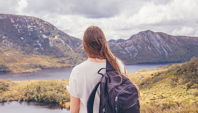 Traveller stands in front of Lake St Clair and Cradle Mountain