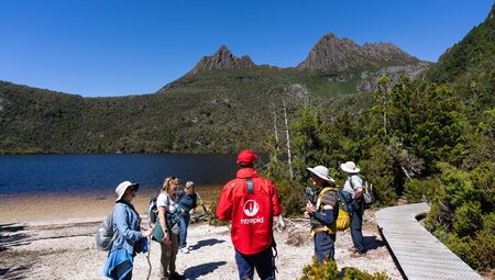 Group standing on the shores of Lake St. Clair looking up Cradle Mountain in Tasmania