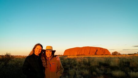 Intrepid travellers pose happily together during a sunset viewing at Uluru in Northern Territory Australia