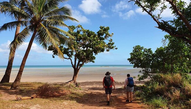 Traveller and leader at the end of a hike to a beach step onto the sand from the last bit of forest in Cape York