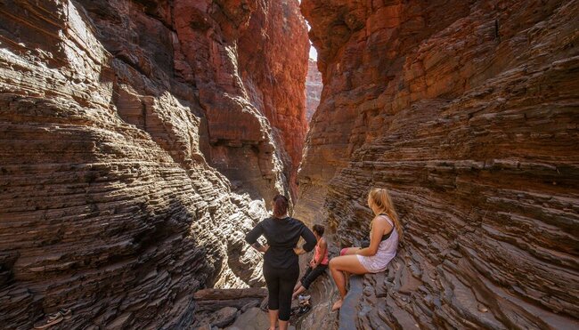 Travellers look as light shines through the openings of Karijini Gorge in Western Australia