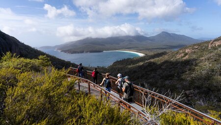 Group of Intrepid travellers look out over Wine Glass Bay from a lookout in Tasmania