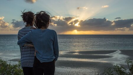 Travellers looking out at Coral Bay at sunset