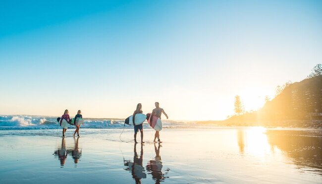 18 to 35 year old Travellers come in from a morning surf on the NSW coast at sunrise