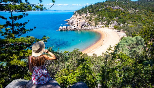 Traveller in sun hat looks out at Magnetic Island Beach