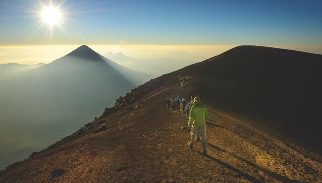 Intrepid travellers approaching Acatenango's peak near Antigua in Guatemala with Fuego beyond