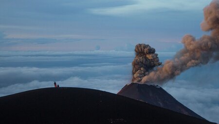 Intrepid travellers stop on the peak of Acatenango watching Volcano Fuego erupt in Guatemala