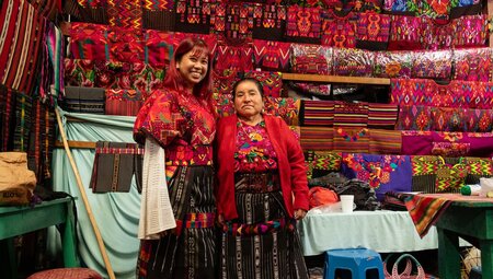 Intrepid traveller smiles happily with local textile merchant after a fitting in Chichicastenango markets