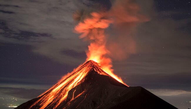 Volcano Fuego eruption seen from the slopes of Fuego, with Antigua's lights behind