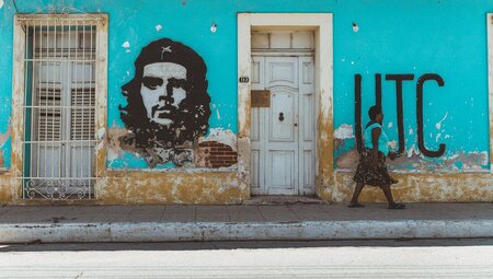 Colourfully painted streets of Trinidad with graffiti of Che Guevara as pedestrian walks by