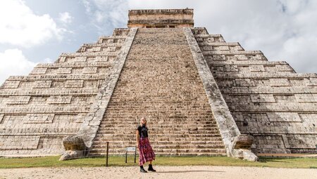 Traveller posing in front of El Castillo Pyramid at Chichen Itza, Mayan ruins in Mexica