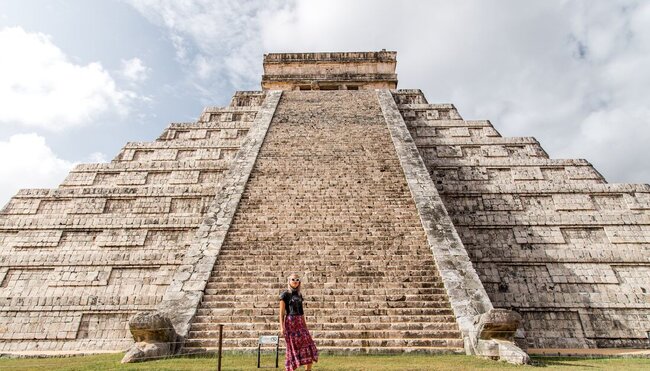 Traveller posing in front of El Castillo Pyramid at Chichen Itza, Mayan ruins in Mexica