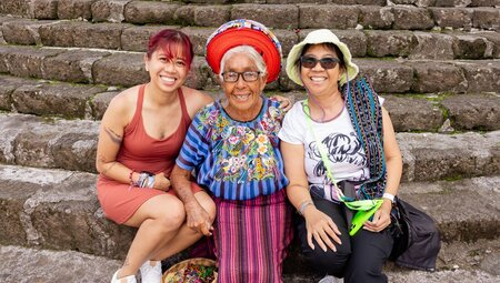 Intrepid travellers sit with a kindly local woman on the streets of Santiago Atitlan's main church in Guatemala