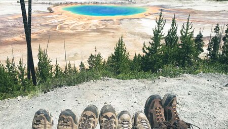 Hikers enjoying the views of the prismatic pools in Yellowstone NP, Wyoming, USA