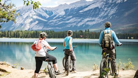 Travellers pausing on their cycling day tour at Edith Lake in Jasper, Canada on an Intrepid Travel tour.