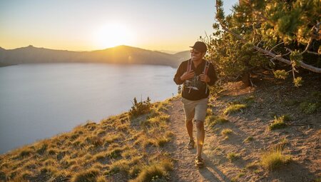Traveller hikes around the rim of Crater Lake National Park in Oregon USA at sunrise
