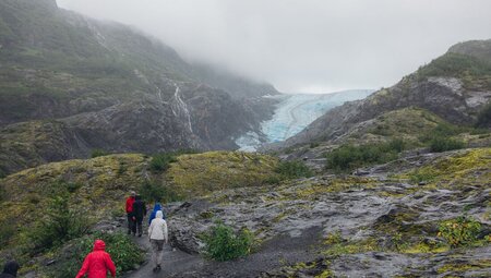 Travellers and leader hiking toward Exit Glacier in the mountains near Seward Alaska