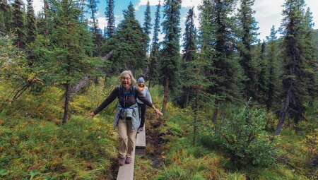 Travellers smile with joy while hiking on a board trail in Denali National Park in Alaska