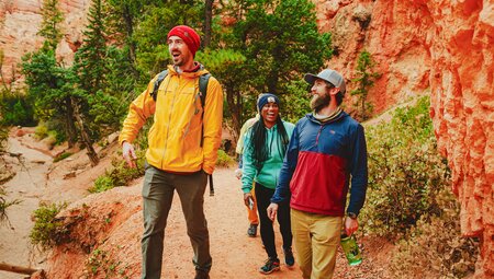 Intrepid travellers talk and laugh together among the bright orange stone and earth of Bryce Canyon's walls on a hike