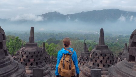 Exploring Borobudur's ancient bell-shaped stupas, looking out over the rainforests of Java