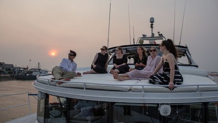 Travellers relaxing on the deck of a sunset cruise in Sanur, Bali