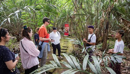 Local guide speaking with travellers at a Salak plantation in the jungles of Sibetan Village, Bali, Indonesia