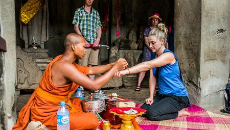 Traveller receiving a blessing wristband from a Buddhist monk in Siem Reap, Cambodia on an Intrepid Travel tour