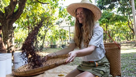 Traveller smiling while tossing cocoa beans in Coca Valley Farm, Thailand