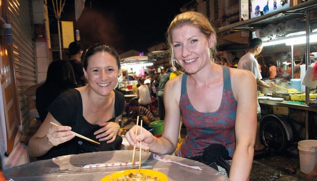Travellers enjoying noodles from hawker street food vendor