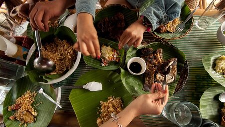Top down shot of travellers sharing a filipino meal with banana leaves