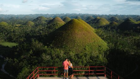 Intrepid traveller couple on viewing platform marvelling at the Chocolate HIlls in Bohol Philippines