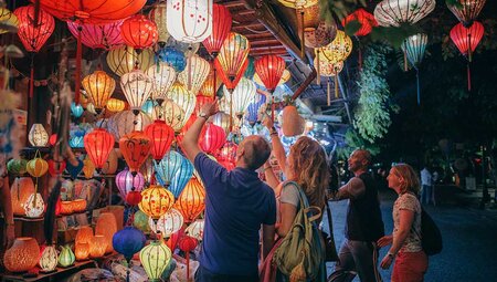 Travellers look at lanterns sold in local market in Hoi An