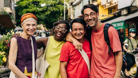 Intrepid travellers pose with leader with happy faces in the streets of Hanoi