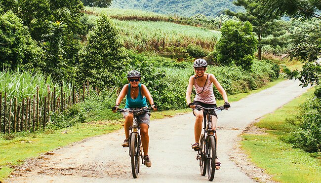 Travellers cycling through the lush vietnamese countryside on an Intrepid Trip.