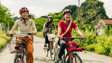 Group of Intrepid travellers and leader with happy faces cycling in Ninh Binh