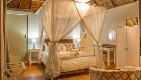 Comfortable warm lit room with mosqutio netted four poster bed near Kurger National Park in South Africa