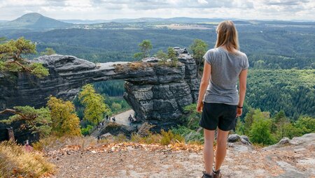 Intrepid traveller stands high taking in Presbischtor Gate in Czechia's mountains