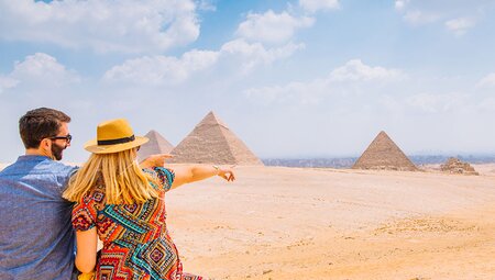XEPE - Couple pointing and admiring the pyramids in Cairo, Egypt on a bright and sunny day