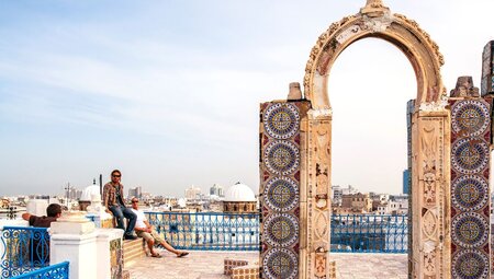 Rooftop relaxation in Tunis's Medina among tiled gates and city views