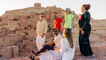 Group of travellers enjoying the sunset with their leader, Ait Benhaddou, Morocco